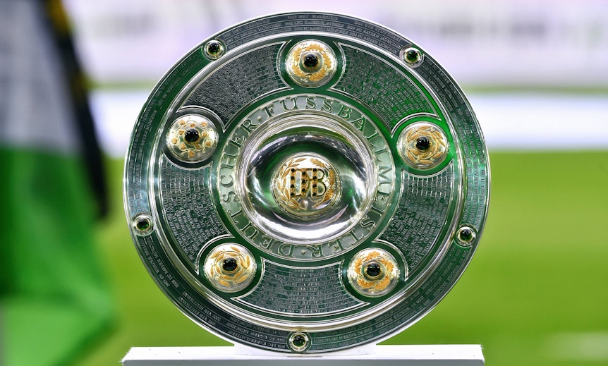 Die Meisterschale der Fußball-Bundesliga, hier zu sehen am 13. August 2021 im Gladbacher Borussia-Park. Im Hintergrund weht eine Fahne von Borussia Mönchengladbach.