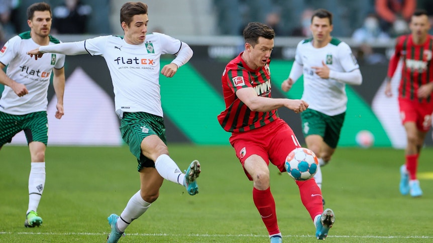 Borussia Mönchengladbach hat am Samstag (12. Februar 2022) den FC Augsburg mit 3:2 besiegt. Das Foto zeigt Borussias Florian Neuhaus beim Duell mit Augsburgs Michael Gregoritsch (r.).