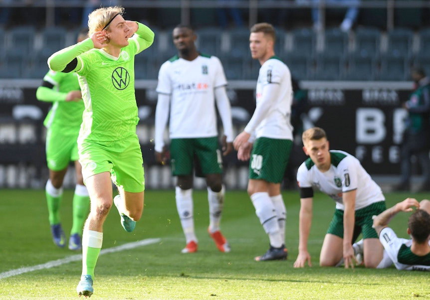 Sebastiaan Bornauw vom VfL Wolfsburg macht eine provokative Geste in Richtung der Fohlen-Fans in der Nordkurve während des Bundesliga-Duells (26. Februar 2022) gegen Borussia Mönchengladbach. Bornauw hält die Hände an die Ohren.
