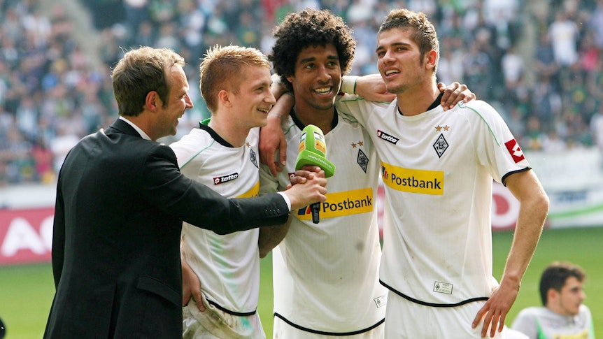 Die ehemaligen Gladbach-Profis (v.r.) Roman Neustädter, Dante und Marco Reus im Gespräch mit Stadionsprecher Torsten Knippertz (l.) am 28. April 2012 im Borussia-Park. Knippertz hält das Stadion-Mikrofon, die Spieler umarmen sich.