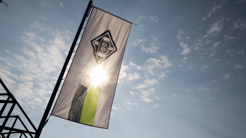 Eine Fahne mit dem Logo von Borussia Mönchengladbach weht am Borussia-Park. Der Verein hat den Verlust aufgrund der Corona-Krise auf «zehn bis 13 Millionen Euro» beziffert. +++ dpa-Bildfunk +++