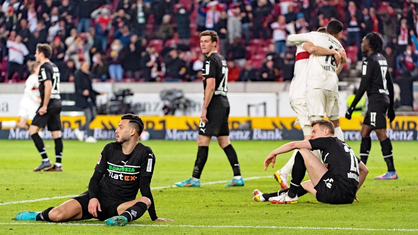 Jubelnde Stuttgarter, gefrustete Gladbach-Spieler wie Ramy Bensebaini (l.) oder Matthias Ginter (r.) beim Bundesliga-Duell am 5. März 2022 in der Mercedes-Benz-Arena. Bensebaini und Ginter sitzen enttäuscht auf dem Spielfeld.