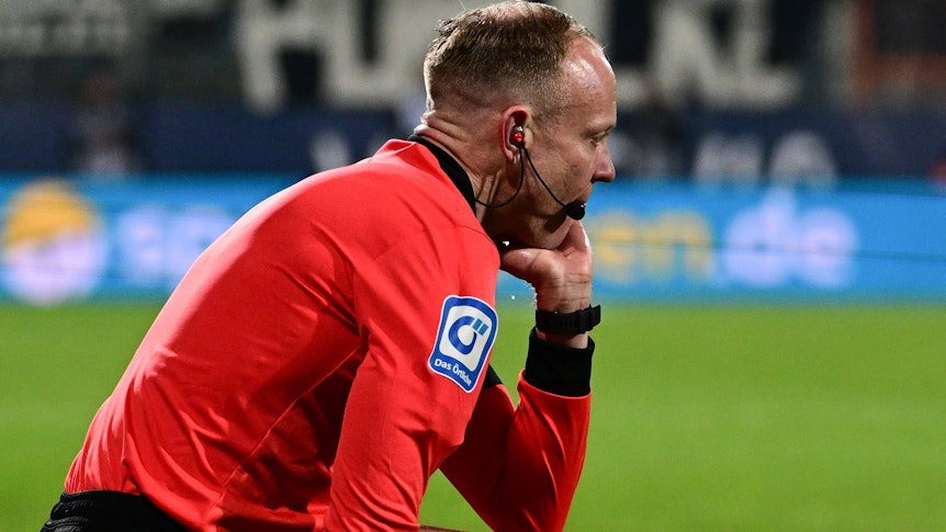 Linienrichter Christian Gittelmann sitzt benommen auf dem Spielfeld: Ihn hat beim Bundesliga-Match zwischen dem VfL Bochum und Borussia Mönchengladbach am Freitag (18. März 2022) ein Becher getroffen, woraufhin die Partie abgebrochen wurde.