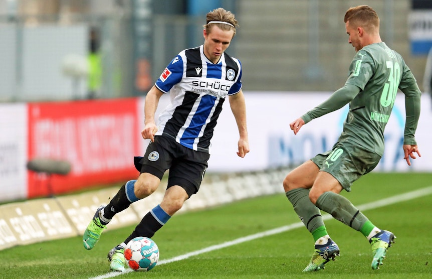 Patrick Wimmer (l.) von Arminia Bielefeld im Zweikampf mit Nico Elvedi (r.) von Borussia Mönchengladbach im Bundesligaspiel am 5. Februar 2022 auf der Alm. Wimmer hat den Ball am Fuß.