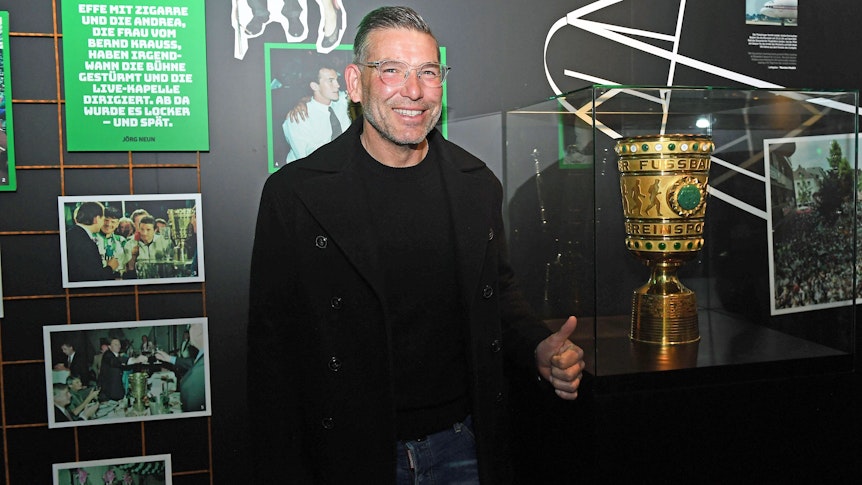DFB-Pokalsieger und Torhüterlegende von Borussia Mönchengladbach, Uwe Kamps, in der Fohlen-Welt am 3. April 2022. Uwe Kamps steht lächelnd, mit dem linken Daumen nach oben, vor dem DFB-Pokal.
