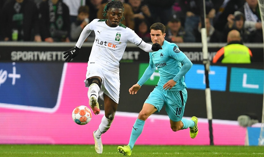 Manu Kone von Borussia Mönchengladbach im Duell mit Marco Meyerhöfer von Greuther Fürth im Bundesliga-Duell am 20. November 2021. Kone nimmt den Ball mit der rechten Fußsohle an. Hinter ihm läuft Meyerhöfer.