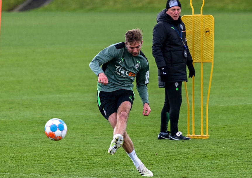 Gladbach-Profi Christoph Kramer am 10. April 2022 beim Torschusstraining im Borussia-Park. Im Hintergrund schaut Co-Trainer Armin Reutershahn zu. Kramer schießt den Ball.