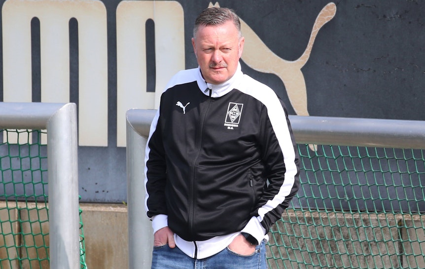 Gladbach-Manager Roland Virkus schaut sich am 14. April 2022 das Training der Profis im Borussia-Park an. Virkus hat die Hände in seinen vorderen Hosentaschen.