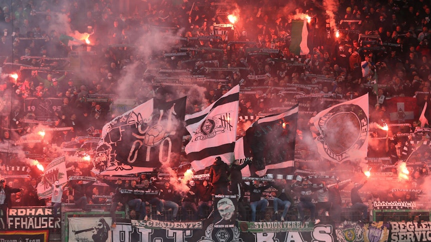 Ultras von Borussia Mönchengladbach zünden Bengalos an beim Bundesligaspiel der Fohlen-Elf im Stadion von Greuther Fürth am 9. April 2022. Andere Fans schwenken ihre Fahnen.