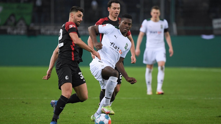 Vincenzo Grifo (l.) und Nicolas Höfler (r.) vom SC Freiburg im Zweikampf mit Breel Embolo von Borussia Mönchengladbach im Hinspiel am 05. Dezember 2022.