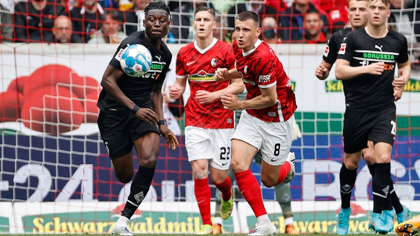 Kouadio Kone von Borussia Moenchengladbach im Kampf um den Ball mit Roland Sallai und Maximilian Eggestein vom SC Freiburg