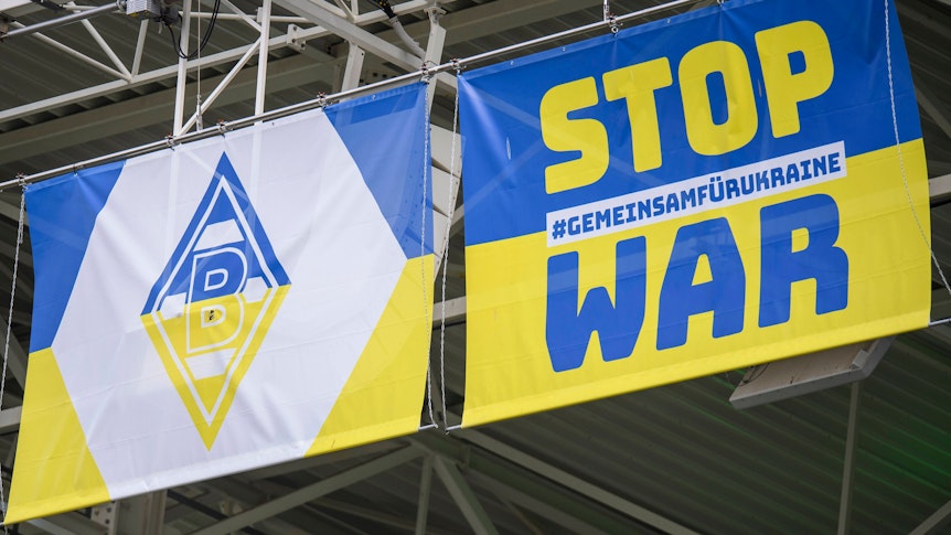 Zwei blau-gelbe Wappen mit Borussia-Logo und Anti-Kriegs-Slogan am 3. April 2022 im Borussia-Park.
