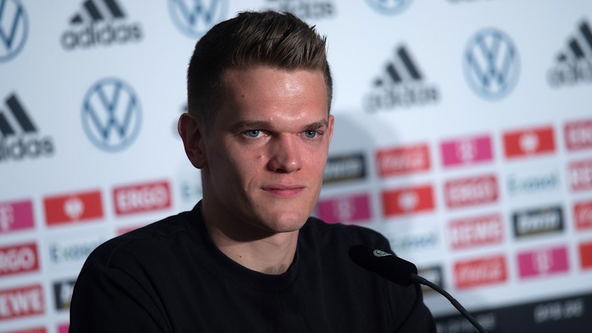 Verteidiger Matthias Ginter spricht bei einer Pressekonferenz der deutschen Fußball-Nationalmannschaft am 23. März 2022. Ginter lächelt.
