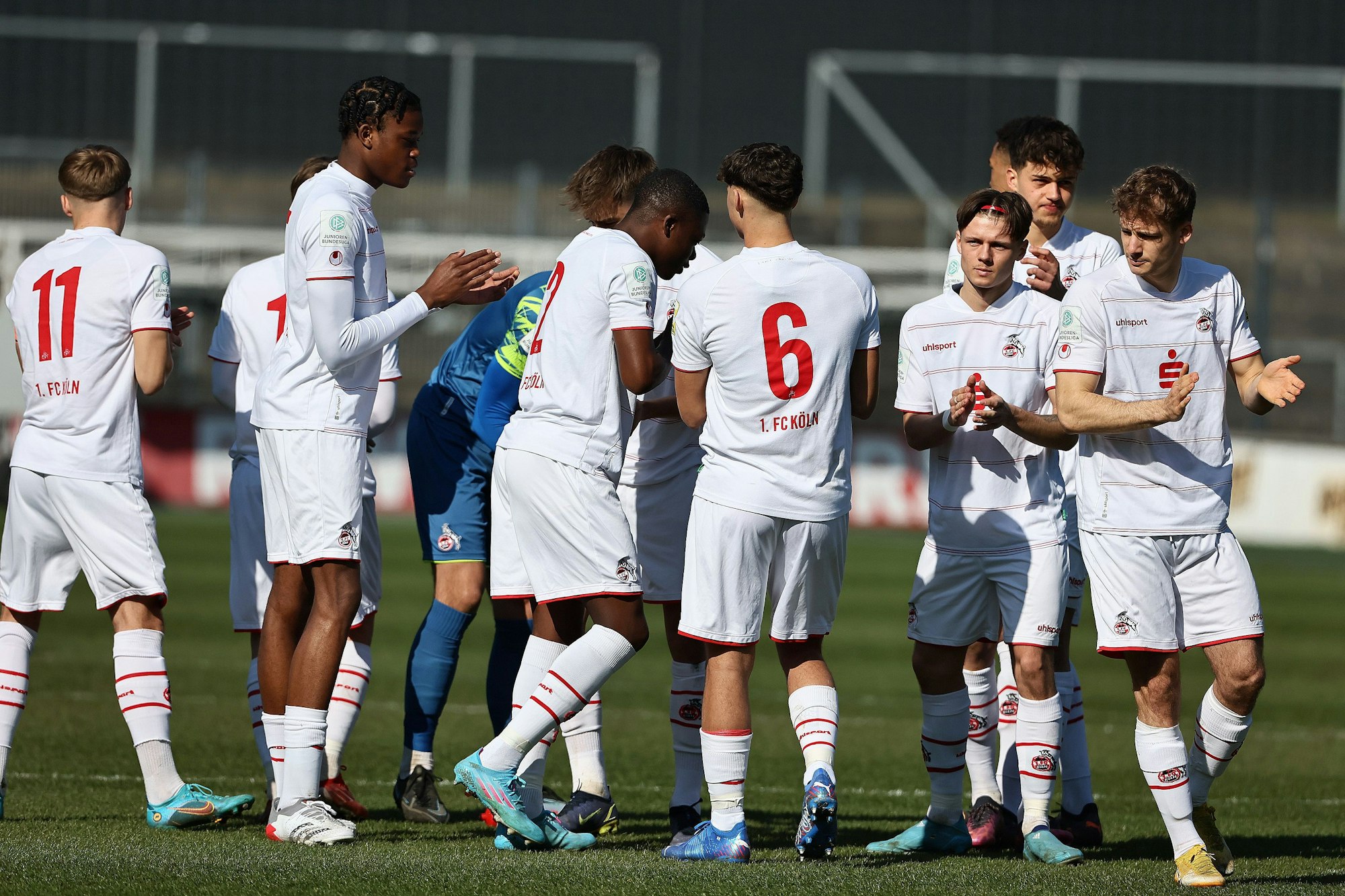 Die Spieler der U19 des 1. FC Köln klatschen sich in einem Spiel ab.
