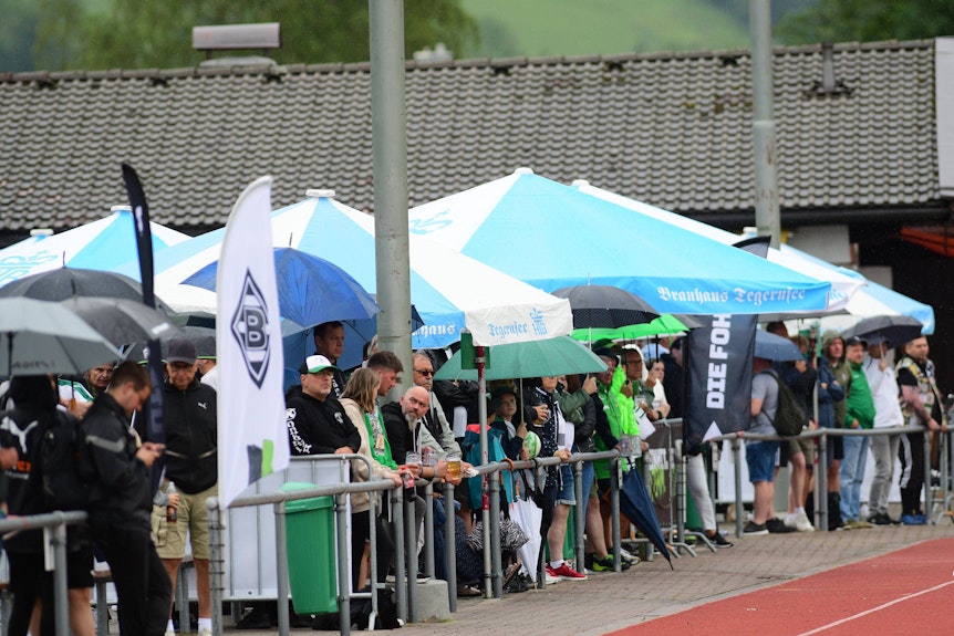 Gleich zum ersten Gladbach-Training am Montag (4. Juli 2022) in Rottach-Egern kamen Hunderte Borussia-Fans trotz Regenschauer auf die Sportanlage Birkenmoos. Die Anhänger schauen bei den Übungen zu.