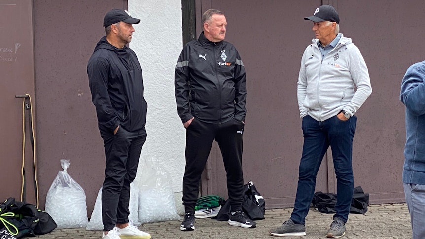 Bundestrainer Hansi Flick, Gladbach-Manager Roland Virkus und Vizepräsident Rainer Bonhof (v.l.n.r.) unterhalten sich am Rande des Borussia-Trainings am Donnerstag (7. Juli 2022) in Rottach-Egern.