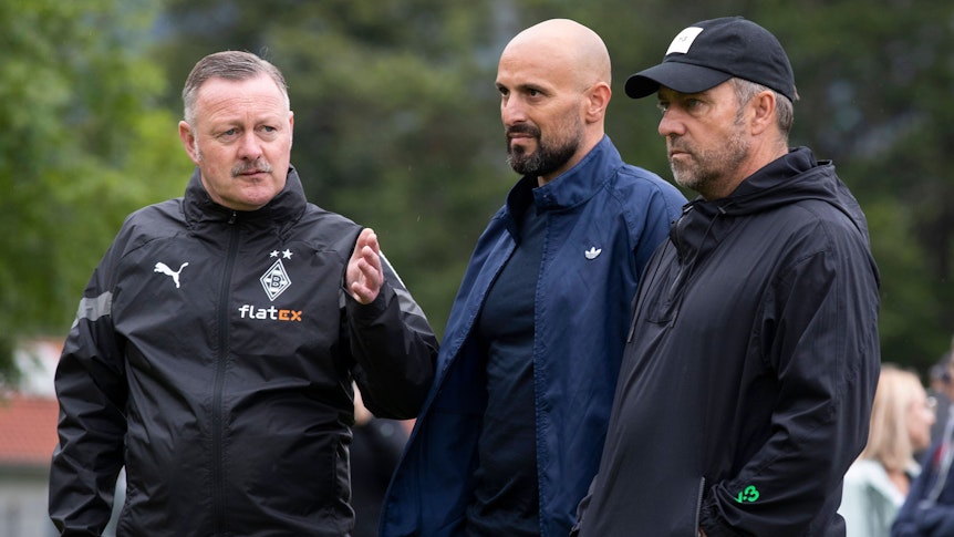 Gladbach-Manager Roland Virkus (l.) im Gespräch DFB-Bundestrainer Hansi Flick (r.) und U21-Nationalcoach Antonio Di Salvo (r.) im Trainingslager der Borussia am Tegernsee in Rottach-Egern. Dieses Foto stammt vom 7. Juli 2022. Virkus macht eine Geste mit der linken Hand.
