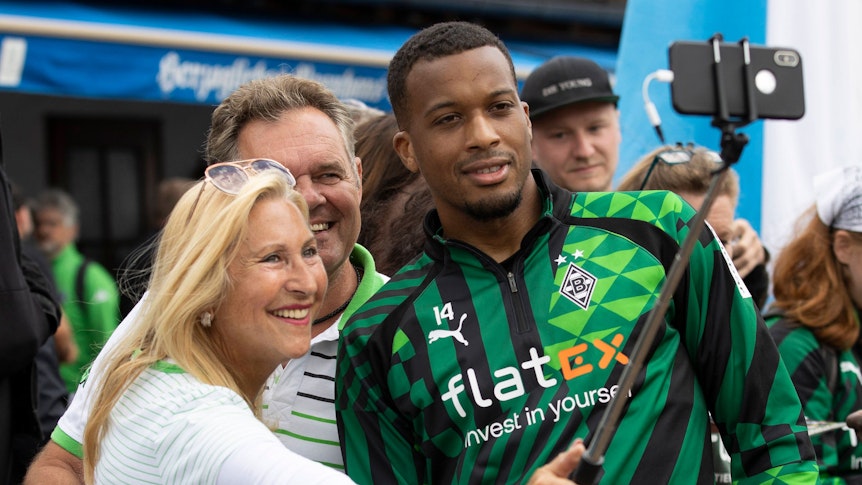 Eine Gemeinschaft! Gladbach-Star Alassane Plea (r.) nimmt sich im Trainingslager von Borussia Mönchengladbach am Tegernsee in Rottach-Egern Zeit für ein Selfie mit Fohlen-Fans. Dieses Foto stammt vom 8. Juli 2022. Plea lächelt in das Handy einer Zuschauerin, die einen Selfie-Stick für ihre Aufnahme benutzt.