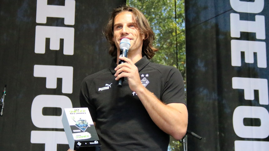 Torhüter Yann Sommer spricht bei der Saisoneröffnung von Borussia Mönchengladbach am 24. Juli 2022 über seine Auszeichnung zum Spieler des Jahres. Sommer hält ein Mikrofon und steht auf einer Bühne, in seiner rechten Hand befindet sich die Trophäe.