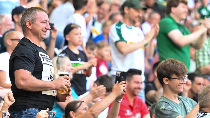 Fans der Gladbacher Borussia bejubeln am 23. Juli 2022 im Borussia-Park einen Treffer der Fohlen-Elf im Testduell gegen Real Sociedad San Sebastian. Ein Anhänger hält einen Bierbecher in seinen Händen. Die Fans klatschen und machen Handy-Fotos.