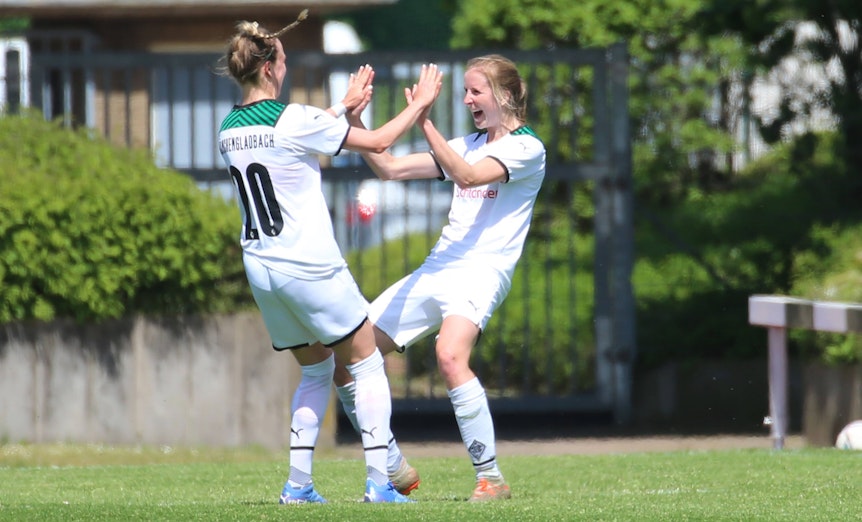 Die Gladbach-Spielerinnen (v.l.) Chantal Reinier Baghuis und Tabea Griss bejubeln einen Treffer im Regionalliga-Duell gegen SV Menden am 8. Mai 2022 im Rheydter Grenzlandstadion. Beide Spielerinnen klatschen sich ab.