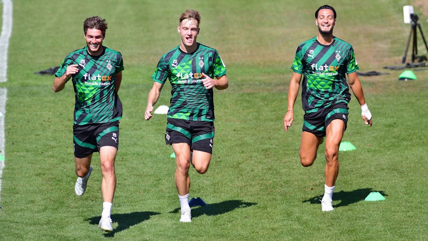 Gute Laune im Training von Borussia Mönchengladbach: Luca Netz (Mitte), Ramy Bensebaini (r.) und Joe Scally (l.) bei der Einheit am Mittwoch (10. August 2022) im Borussia-Park. Die drei Gladbach-Profis laufen über das Spielfeld.