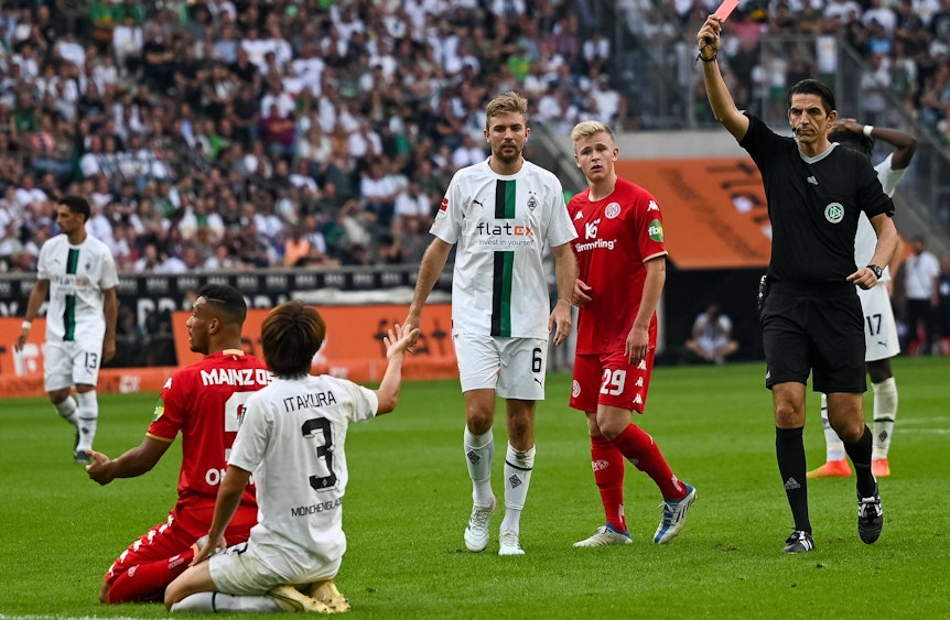 Schiedsrichter Deniz Aytekin (r.) zeigt Gladbach-Verteidiger Ko Itakura (kniend, im weißen Trikot) die Rote Karte nach einer Notbremse im Bundesliga-Duell gegen Mainz 05 (4. September 2022) im Borussia-Park. Aytekin hält die Rote Karte in der Hand.