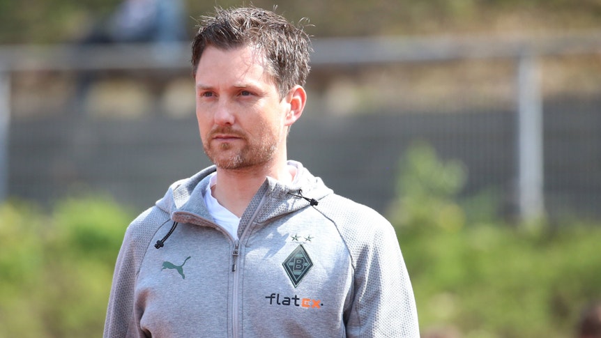Nachwuchs-Chef Mirko Sandmöller von Borussia Mönchengladbach, hier zu sehen am 23. April 2022 im Rheydter Grenzlandstadion, droht der Abgang eines Talentes. Er schaut nach vorne, er trägt eine graue Trainingsjacke.