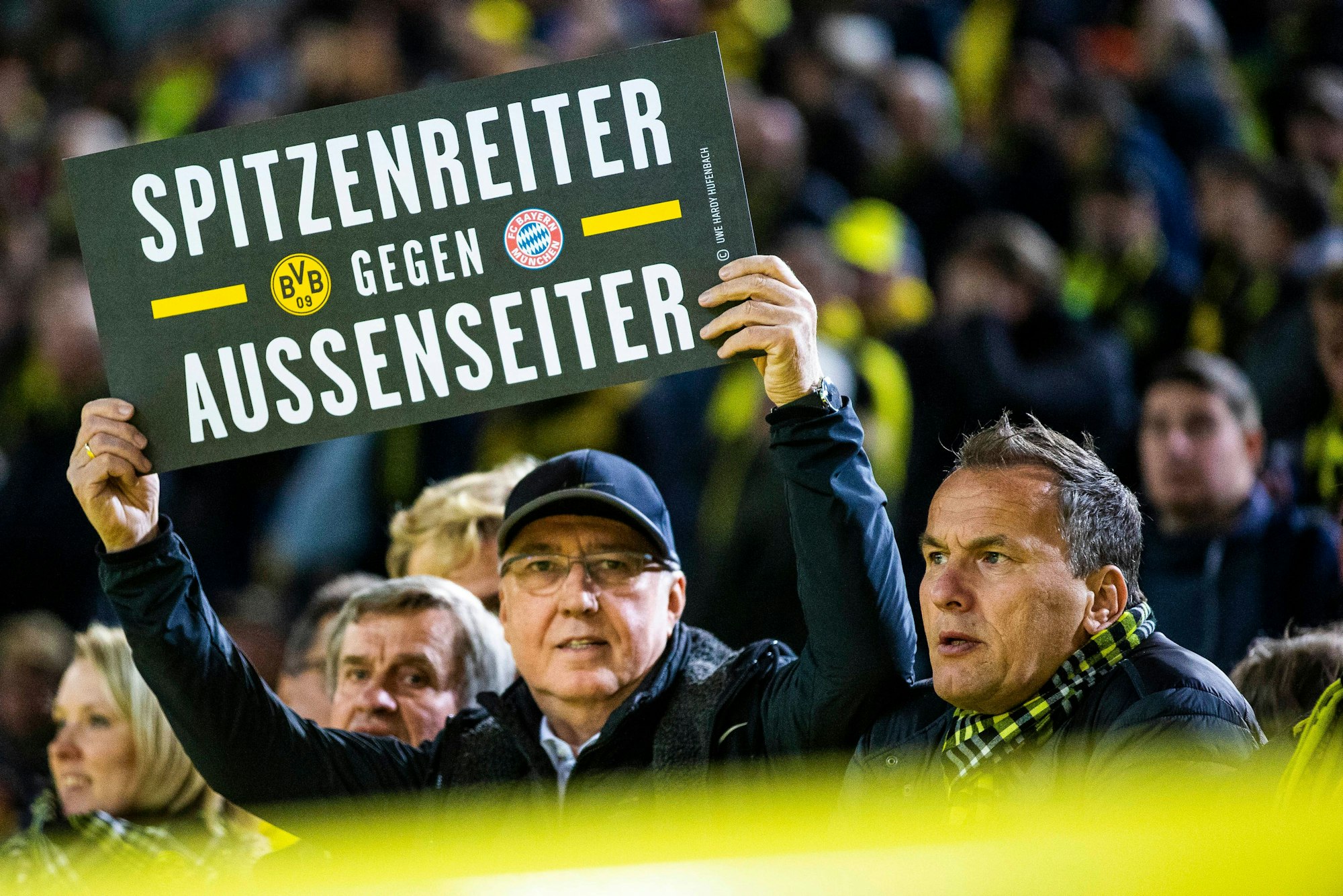 Ein Fan hält in Dortmund ein Plakat mit der Aufschrift Spitzenreiter gegen Außenseiter in die Luft.