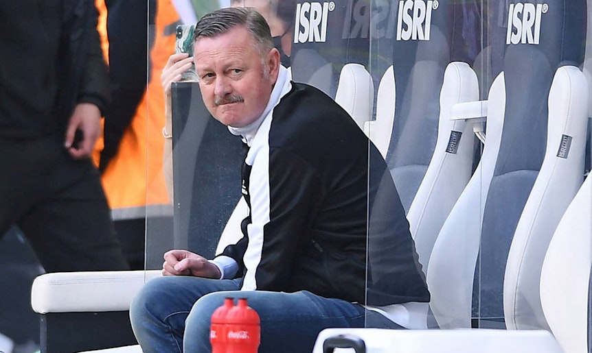 Ein enttäuschter Blick: Gladbach-Manager Roland Virkus sitzt bei der Derby-Niederlage gegen den 1. FC Köln am 16. April 2022 auf der Spielerbank im Borussia-Park. Virkus trägt eine schwarz-weiße Puma-Jacke.