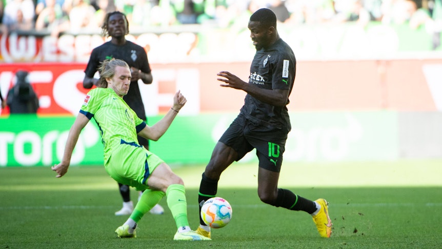 Gladbach-Stürmer Marcus Thuram (r.) im Zweikampf mit Patrick Wimmer (l.) vom VfL Wolfsburg während des Bundesliga-Duells am Samstag (15. Oktober 2022) in der Autostadt. Beide Spielen haben den Ball im Blick.