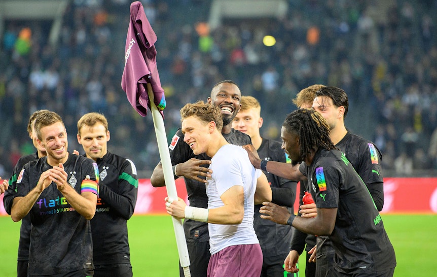 Jubel im Borussia-Park: Die Gladbach-Profis um Stürmer Marcus Thuram feiern nach der 4:2-Gala (11. November 2022) gegen Borussia Dortmund den Heim-Dreier und Torhüter-Talent Jan Olschowsky, der stark gehalten hatte. Olschowsky hält die Eckfahne mit seinem Trikot in der linken Hand.