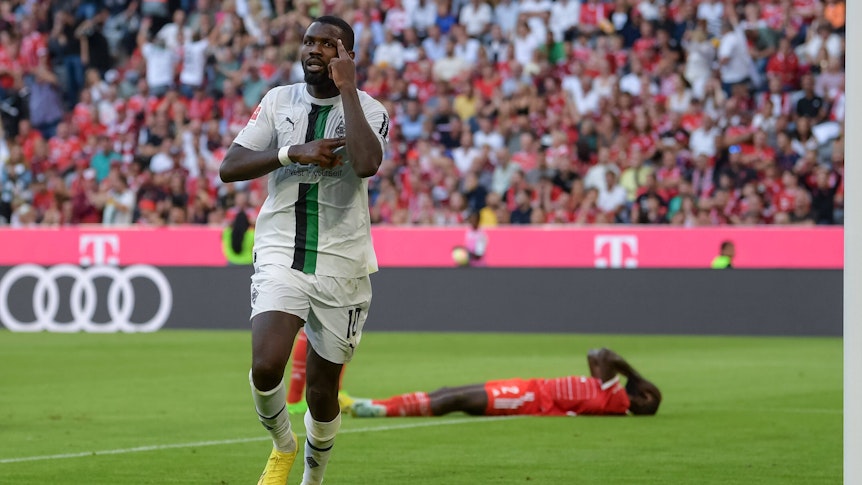 Marcus Thuram erzielt ein Tor für Borussia Mönchengladbach gegen den FC Bayern München am 27. August 2022 und jubelt, während Bayern-Verteidiger Dayot Upamecano auf dem Boden liegt.