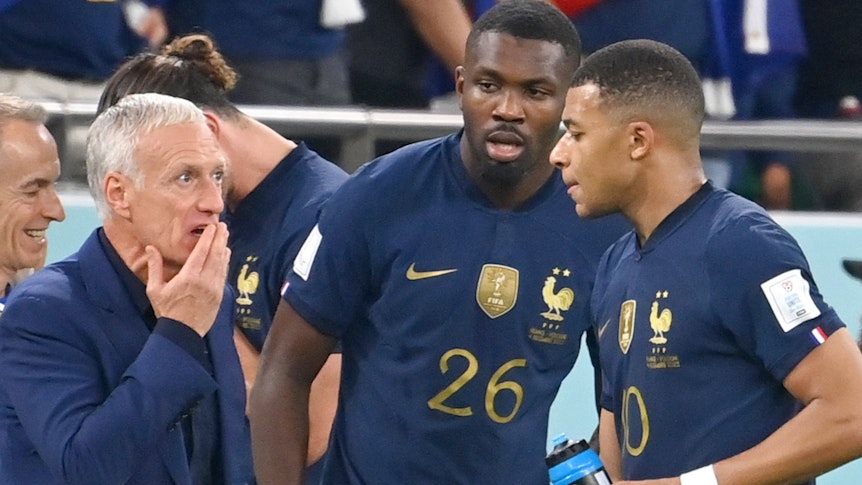 Marcus Thuram (M.) ist der letzte Gladbach-Star bei der Fußball-Weltmeisterschaft in Katar. Auf diesem Foto ist der Stürmer gemeinsam mit Kylian Mbappe (r.) und Trainer Didier Deschamps (l.) am 4. Dezember 2022 zu sehen. Deschamps spricht an der Seitenlinie mit den beiden Spielern.