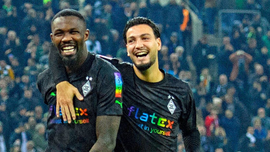 Pure Freude: Die Gladbach-Profis Marcus Thuram (l.) und Ramy Bensebaini (r.) bejubeln den Bundesliga-Sieg gegen Borussia Dortmund am 11. November 2022 im Borussia-Park. Bensebaini umarmt Thuram, beide Borussia-Profis strahlen vor Glück.