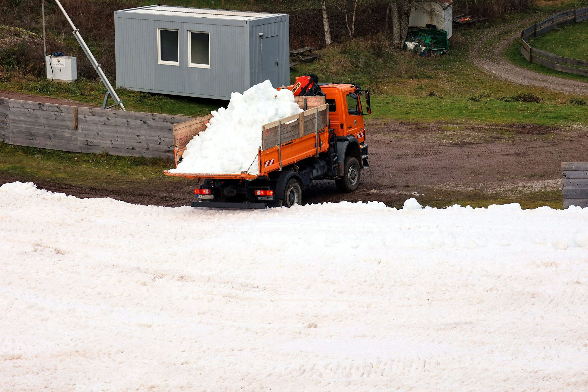 Ein Lastwagen kippt Altschnee in den Schanzenauslauf.