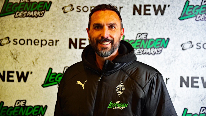 Ex-Gladbach-Kapitän Martin Stranzl, auf diesem Foto am 17. Dezember 2022, vor dem Legendenspiel im Borussia-Park, zu sehen. Stranzl steht vor einer Werbe-Tafel, er lächelt in die Kamera.
