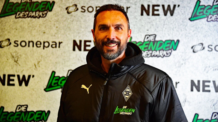 Ex-Gladbach-Kapitän Martin Stranzl, auf diesem Foto am 17. Dezember 2022, vor dem Legendenspiel im Borussia-Park, zu sehen. Stranzl steht vor einer Werbe-Tafel, er lächelt in die Kamera.