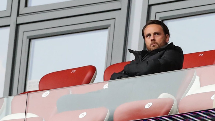 Christopher Vivell, hier am 1. Oktober 2022 bei einem Bundesliga-Spiel zwischen RB Leipzig und dem VfL Bochum, auf roten Ledersitzen im Stadion sitzend und grimmig in die Ferne schauend.