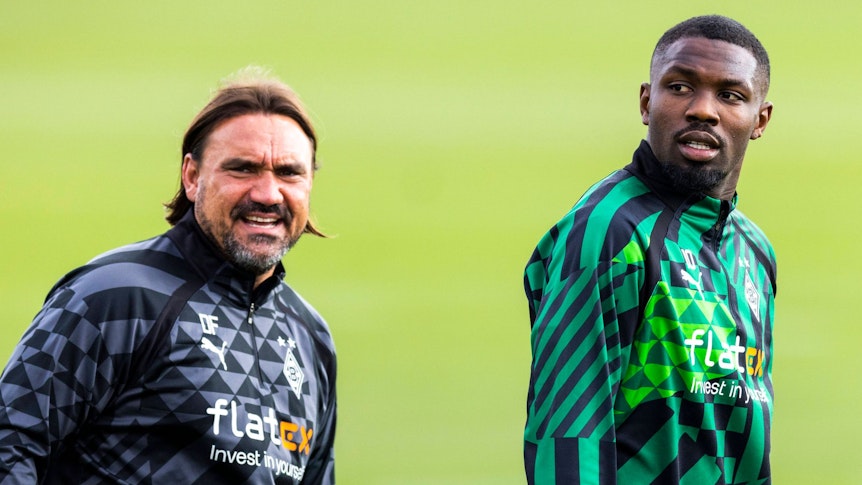 Daniel Farke (l.), Trainer von Borussia Mönchengladbach, und Marcus Thuram stehen auf dem Trainingsplatz im Borussia-Park nebeneinander. Farke und Thuram tragen Gladbach-Trainingskleidung.