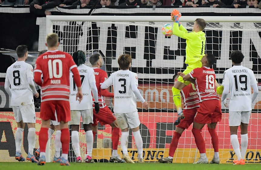 Jonas Omlin, Torwart von Borussia Mönchengladbach (in gelb), lässt den Ball fallen, Dion Beljo (verdeckt) trifft zum vermeintlichen 1:0 für den FC Augsburg. Das Tor am 25. Januar 2023 zählt aber aufgrund einer Abseitsstellung nicht.