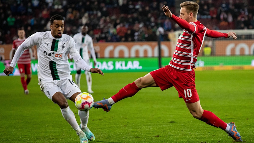 Die Fohlen haben am Mittwoch (25. Januar 2023) ein 0:1 beim FC Augsburg kassiert. Das Foto zeigt Alassane Plea (l.) von Borussia Mönchengladbach, hier beim Zweikampf mit Arne Maier (r.) vom FCA.