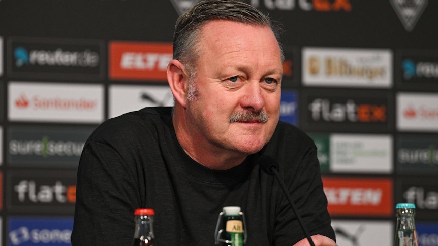 Roland Virkus, Manager von Borussia Mönchengladbach, bei einer Pressekonferenz am 20. Januar 2023 im Borussia-Park. Er schaut verschmitzt und ernst und trägt einen schwarzen Pullover.