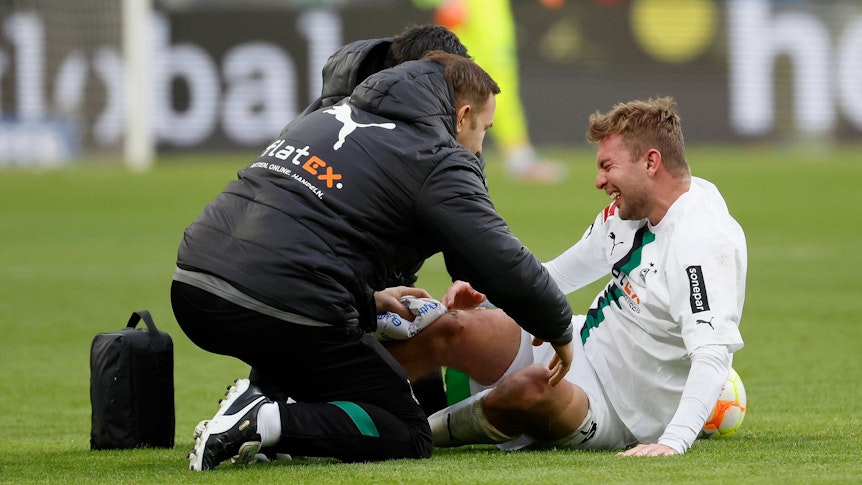 Das tut weh! Christoph Kramer (r.) von Borussia Mönchengladbach ist beim Bundesliga-Duell in Hoffenheim (28. Januar 2023) übel gefoult worden. In dieser Szene wird er behandelt. Er sitzt auf dem Rasen.