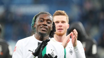 Gute Laune bei Manu Koné von Borussia Mönchengladbach. Der Franzose feierte am Samstag (28. Januar 2023) mit seinem Team einen 4:1-Sieg bei der TSG 1899 Hoffenheim. Das Foto zeigt ihn im weißen langärmligen Trikot und schwarzen Handschuhen in die Hände klatschend.