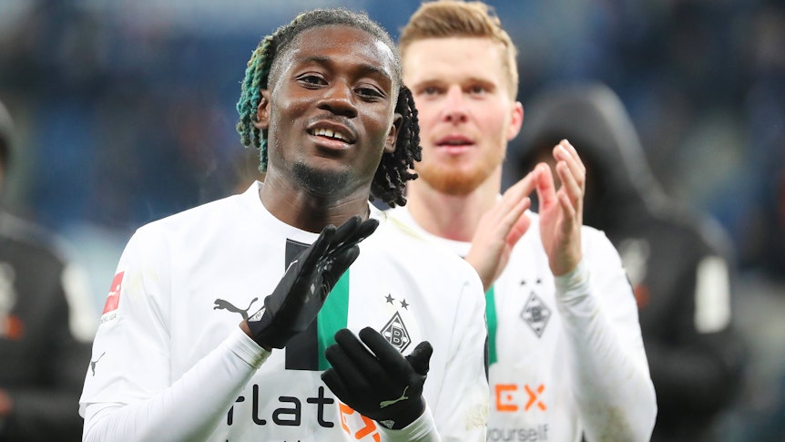 Gute Laune bei Manu Koné von Borussia Mönchengladbach. Der Franzose feierte am Samstag (28. Januar 2023) mit seinem Team einen 4:1-Sieg bei der TSG 1899 Hoffenheim. Das Foto zeigt ihn im weißen langärmligen Trikot und schwarzen Handschuhen in die Hände klatschend.