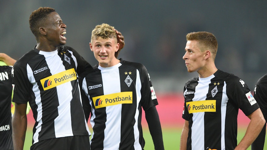 Denis Zakaria (l.), Michael Cuisance (M.) und Thorgan Hazard stehen nach dem Bundesliga-Spiel von Borussia Mönchengladbach gegen den VfB Stuttgart am 19. September 2017 in schwarz-weißen Gladbach-Trikots vor der Fankurve.