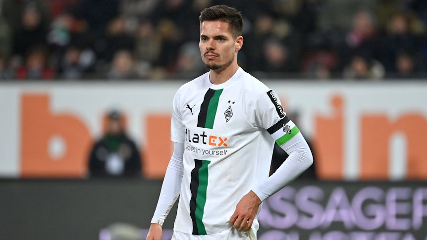 DFB-Nationalspieler Julian Weigl hat sich bei Borussia Mönchengladbach in den Fokus gespielt, auf diesem Foto trägt die Leihgabe von Benfica Lissabon die Kapitänsbinde am 25. Januar 2023 in Augsburg. Weigl schaut nach vorne, er zupft an seinem Trikot rum.
