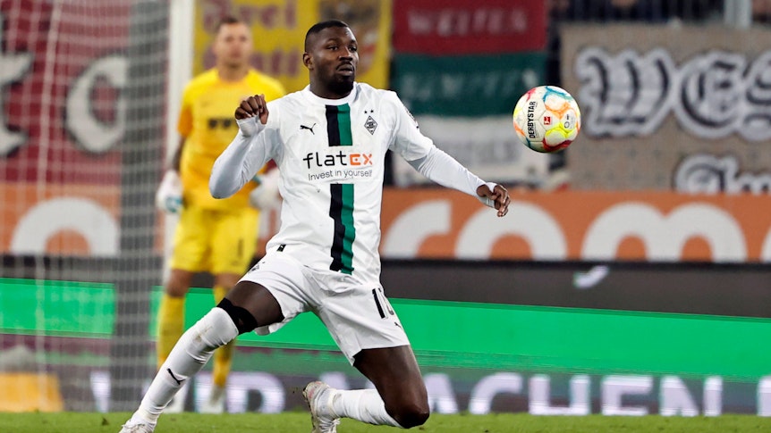 Marcus Thuram schaut im Bundesliga-Spiel von Borussia Mönchengladbach beim FC Augsburg am 25. Januar 2023 fokussiert auf den fliegenden Ball. Thuram trägt das weiße Gladbach-Heimtrikot.