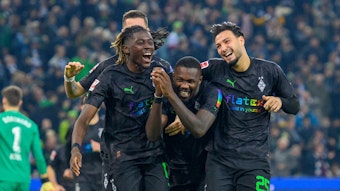 Manu Koné, Marcus Thuram und Ramy Bensebaini bejubeln einen Treffer von Borussia Mönchengladbach gegen Borussia Dortmund am 11. November 2022, feiern Arm in Arm und lachen. Das Gladbach-Trio trägt schwarze Trikots mit einem speziellen Regenbogen-Flock, das Trikot wurde nur beim BVB-Heimspiel am 15. Spieltag der Bundesliga-Saison getragen.